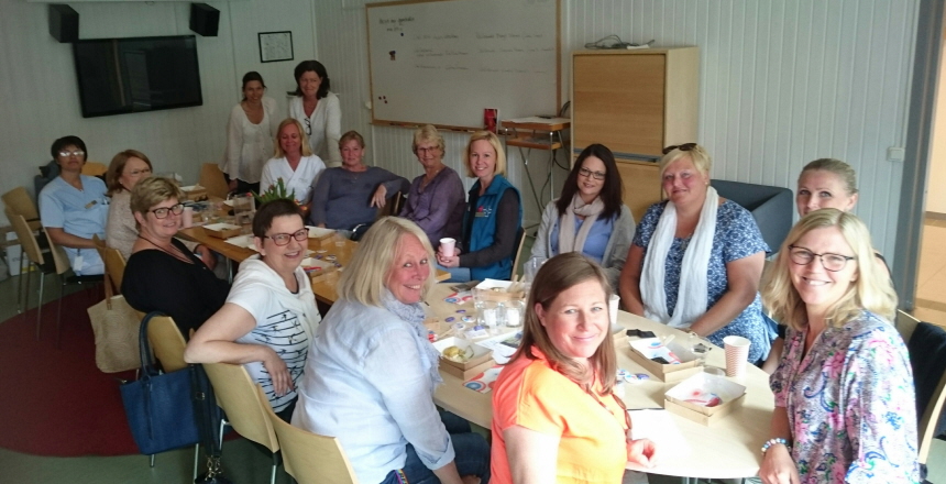 Barnmorskor från Varberg och Falkenberg på Guldkantsmöte 160518. Fjorton personer, alla kvinnor, sitter runt ett konferensbord och två kvinnor står upp. Alla tittar in i kameran.