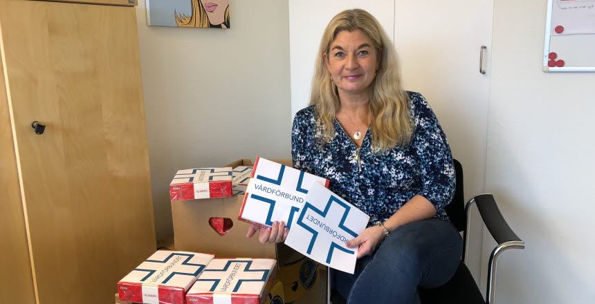 Kvinna med långt ljust hår sitter på en stol och med en hög chokladaskar bredvid sig