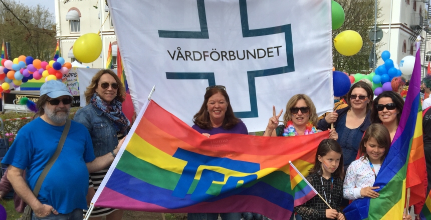 En stor Vårdförbundet-flagga omgiven av människor, ballonger och Pride-flaggor