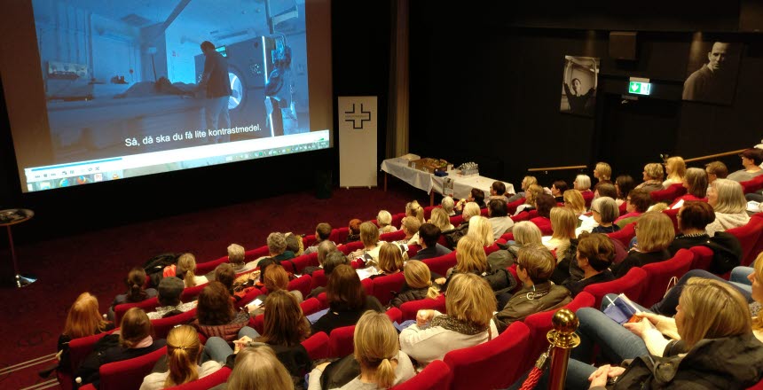 Biosalong som är fylld med sittande personer. Bilden är bakifrån salongen så man ser filmduken.