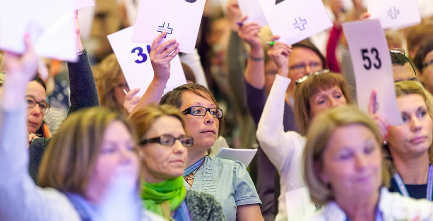 En samling kvinnor håller upp röstkort med siffror på