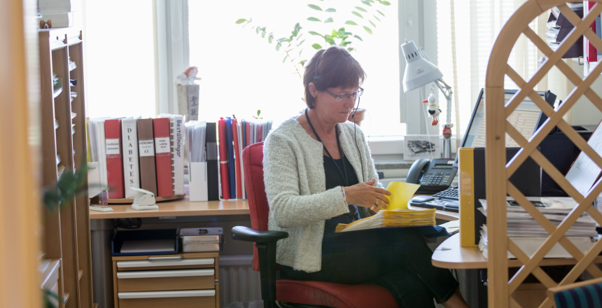 En kvinna som sitter vid sitt skrivbord och går igenom dokumentation