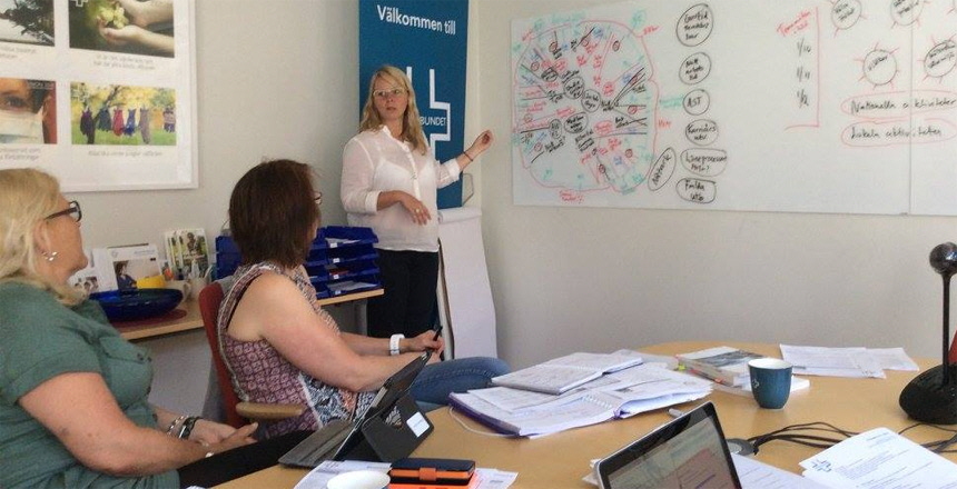 styrelserum med tre ledamöter och en skriver på whiteboardtavla