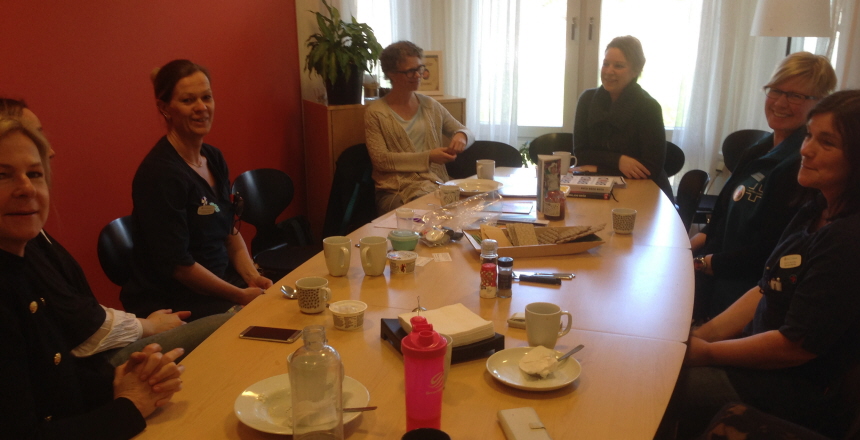 Personal på Säröledens Vårdcentral sitter kring ett konferensbord och samtalar och fikar