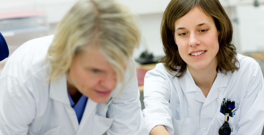 Biomedicinska analytiker tittar på en datorskärm i ett rum på Karolinska sjukhuset. Bilden är tagen framifrån.