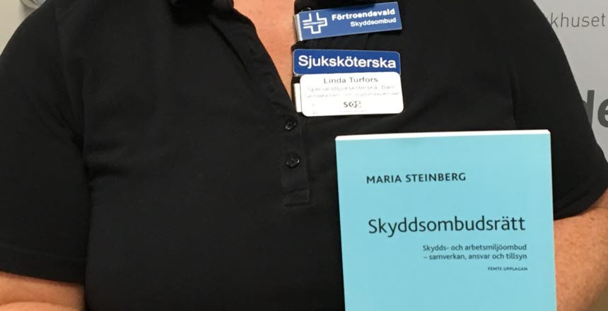 Förtroendevald håller boken Skyddsombudsrätt i handen