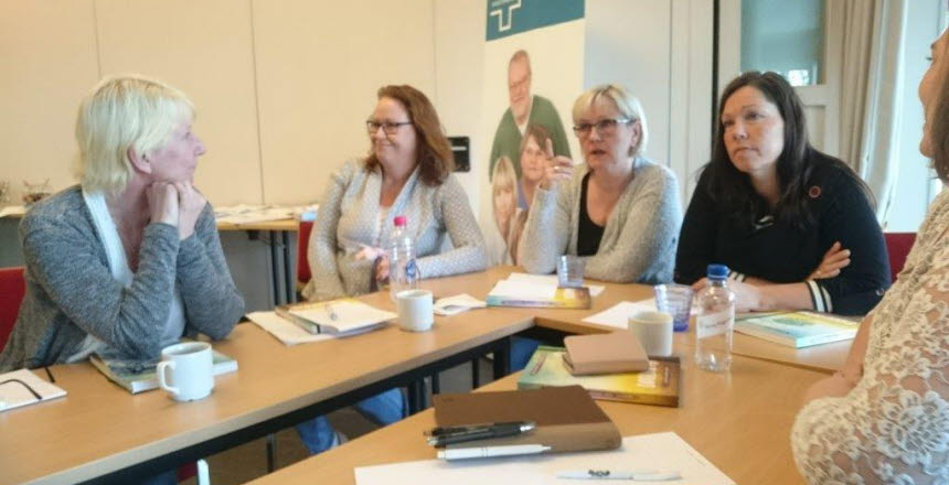 Fem civilklädda kvinnor som sitter vid ett konferensbord