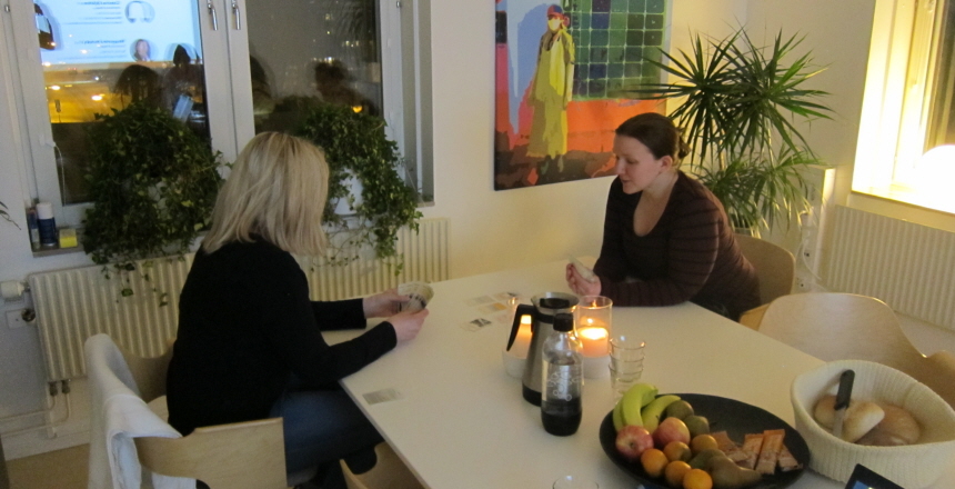 Två kvinnor sitter vid ett bord och samtalar och fikar