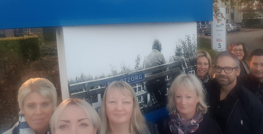 En grupp människor står framför en skylt där det står